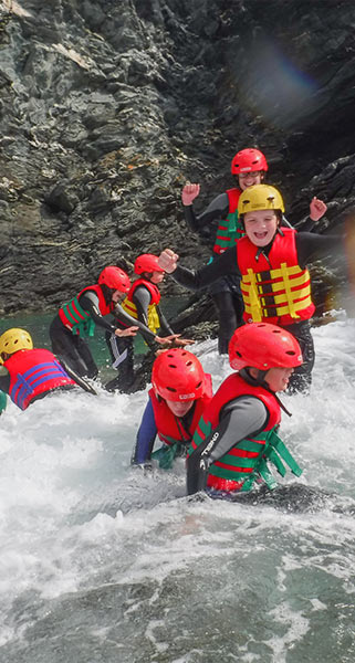 A group of kids enjoy traversing rocks on their Coasteering trip